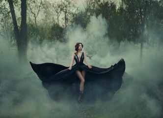 Fantasy gothic woman dark queen bare long legs walks in fog. black dress fly in different...