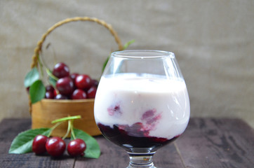 Cherry yogurt dessert and ripe cherry on a wooden table. Summer dessert.