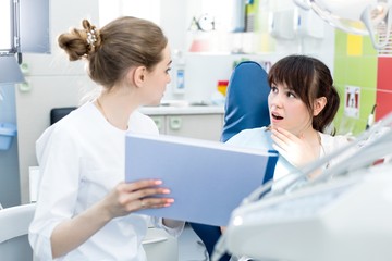 Woman dentist shows the patient the bad results of the examination in the dental clinic