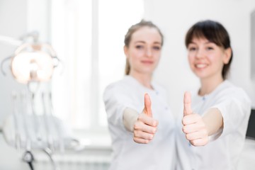 Two dentists in uniform stand in the dental office gesturing hands class