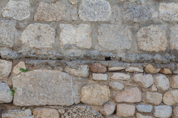 The wall is lined with stones. Building with cobblestones. Background of stones. The texture of the walls in the exterior. Natural stone as a building material.