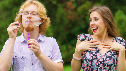 Couple blowing soap bubbles, having fun