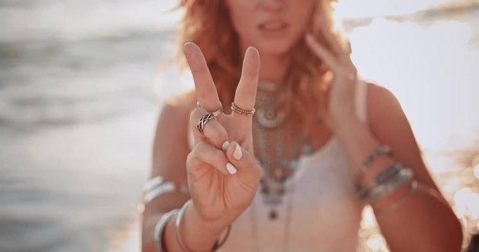 Hippie woman making a peace sign at the beach