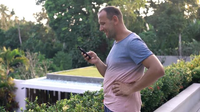 Man sending sms, texting on terrace at country house

