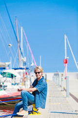 Blonde man sitting near harbor in summer