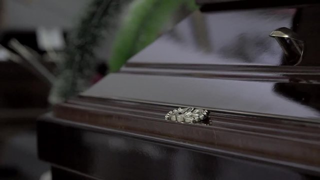 Funeral and mourning concept. Close up handheld shot of details of brown wooden coffin in church.