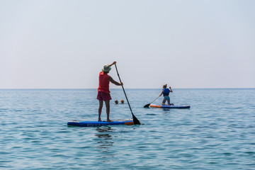 MONTENEGRO, BUDVA - JUNE 05/2017: tourists are engaged in rowing on the board (SUP) on the surface of the calm sea.