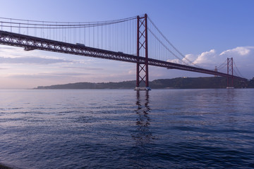 Huge suspension bridge over the river. View of the river, the clear sky and the bridge.