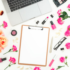 Laptop, clipboard, roses flowers, cosmetics and accessories on white background. Flat lay. Top view. Freelancer office composition