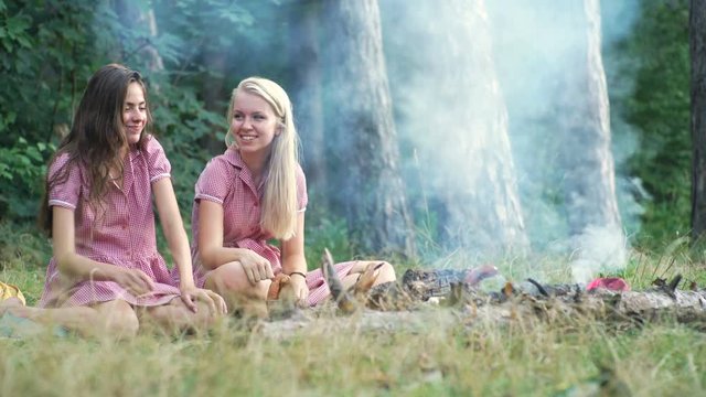 Two young women in pin up style having fun at a picnic in the park in the sunset. Summer, holidays, vacation, happy people concept - smiling girlfriends. Girlfriends on picnic.