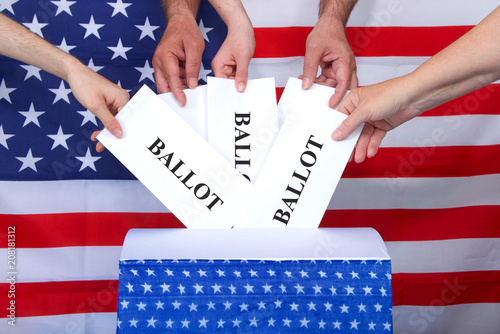 hands placing ballots in a voting box, American flag in background. Anyone over the age of 18 on election day and a citizen of the United States is eligible to vote. Voter turnout fluctuates in the US