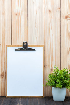 Clipboard blank white paper sheet with little decoration tree in white vase on wooden background, memo template design