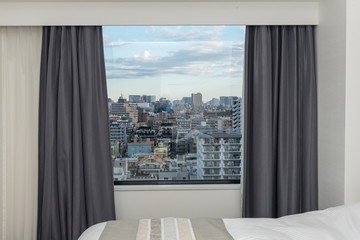 Beautiful view from the bedroom with window curtains and cityscape, blue sky, modern home decor.