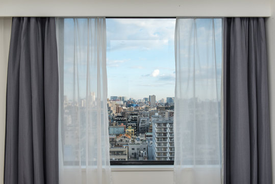 Beautiful View From The Bedroom With Window Curtains And Cityscape, Blue Sky, Modern Home Decor.