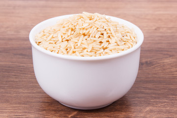 Brown rice in white glass bowl, healthy nutrition