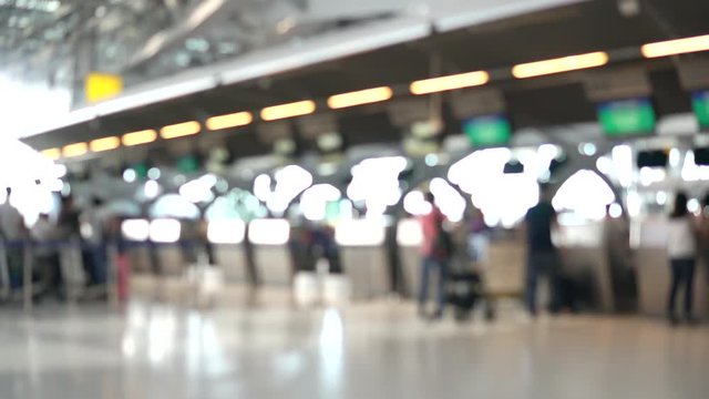 Blurred footage of passengers walking to check-in counter at International airport terminal. 4K video with defocused effect.