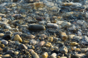pebble stones on the sea beach, the rolling waves of the sea with foam