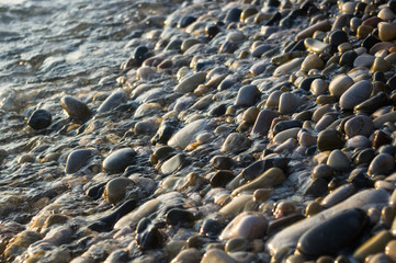 pebble stones on the sea beach, the rolling waves of the sea with foam