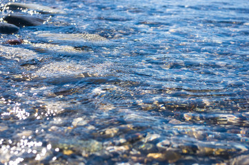 sea pebble beach with multicoloured stones, waves with foam