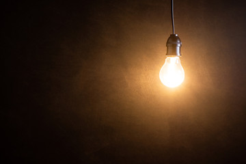 Brightness tungsten light bulb hanging at dark room