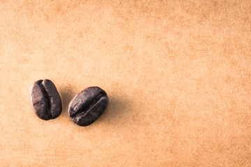 Two of roasted coffee beens on space of rough paper background