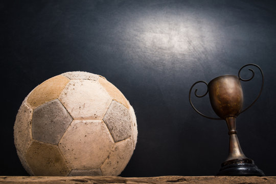 still life photography : old football and vintage trophy on old wood table in championship concept