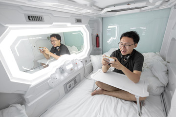man using smartphone in the capsule hotel.