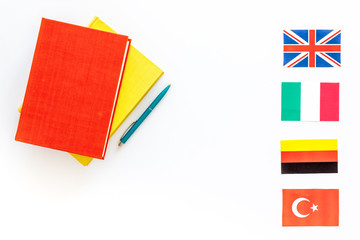 Language study concept. Textbooks or dictionaries of foreign language near flags on white backgrond top view copy space
