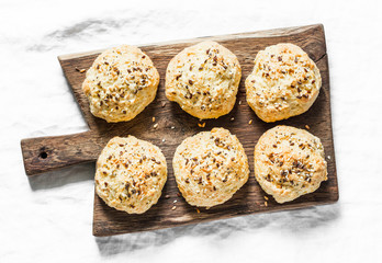 Cheese buns on a cutting rustic board on a light background, top view. Delicious breakfast, brunch, snack