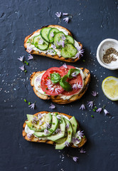 Variations of sandwiches - with cream cheese, avocado, tomato and cucumber on a dark background, top view. Healthy diet food concept. Flat lay