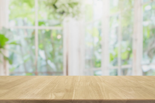 Empty wood table top and blurred of interior room with window view green from tree garden background background - can used for display or montage your products.