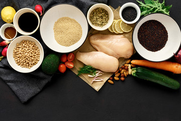 Healthy food clean eating Сhicken breast vegetables nuts chickpeas quinoa seeds dark stone background copy space top view