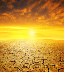 Dry country with cracked soil at sunset. Global warming concept.