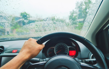 driving car on the road,Driver's hands on the steering wheel inside of a car on a rainy day