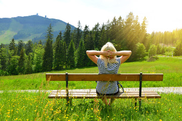 Tourist sitting on a bench overlooking the mount Grosser Arber in National park Bayerische Wald, Germany.