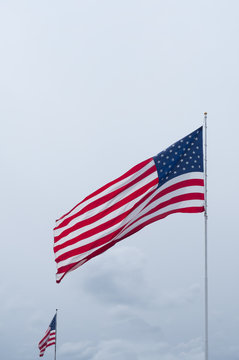 Two Unfurled American Flags Against a Cloudy Sky
