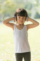 Asian cute kid listening to music on headphones and enjoying in nature background