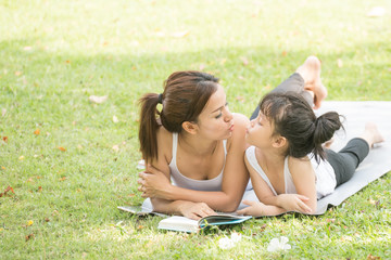 Naklejka na ściany i meble Mother and daughter relaxing in park.She reading a fairytale to her daughter