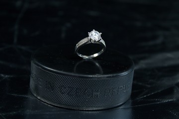 Naklejka premium Engagement Ring on hockey puck with the inscription `Czech Republic` on the SILVER background.Black puck with Engagement Ring on SILVER background. Will you marry me?