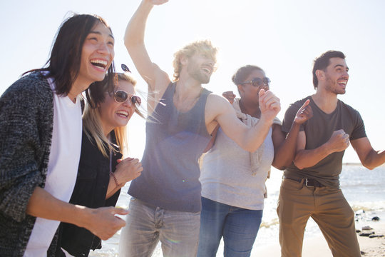 Group of multiracial young people laughing while having fun during party on beach. 
