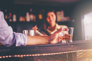 Glass handles are placed on the bar in the night club. There is a bartender standing by for service as background.