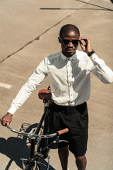 Fototapeta na wymiar Fashionable african american man standing by his bicycle on street