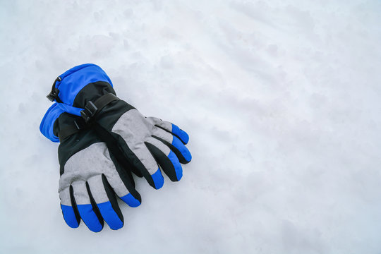 Blue and gray modern skiing gloves on mountain white snow