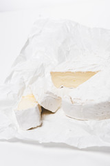 close-up shot of sliced brie cheese on crumpled paper and on white surface