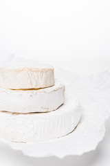 close-up shot of stack of brie cheese heads on crumpled paper and on white surface