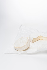 close-up shot of brie cheese on crumpled paper and on white surface
