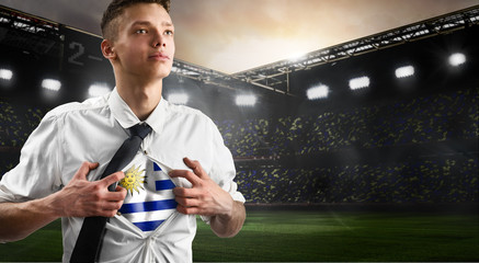 Uruguay soccer or football supporter showing flag under his business shirt on stadium.