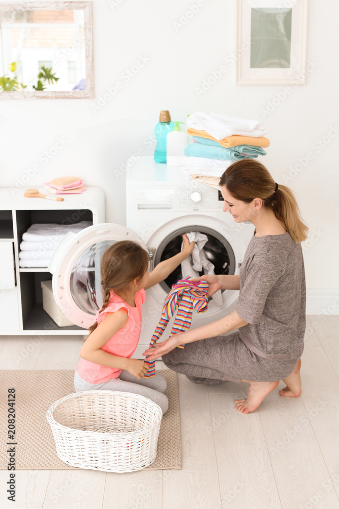 Poster Housewife with little daughter doing laundry at home