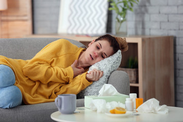 Sick woman suffering from cold on sofa at home