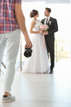 Professional photographer with camera and wedding couple in studio